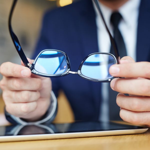 Human hands holding eyeglasses over touchpad